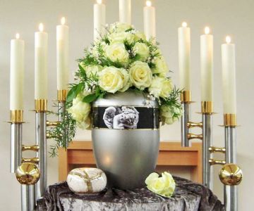 Urnenbeisetzung mit Dekoration aus Rosen und Kerzen